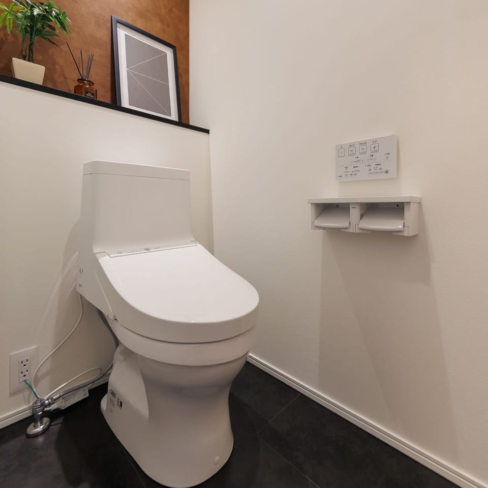 掃除のしやすさに定評のあるTOTO製のトイレ。アクセントにヴィンテージ感のあるクロスを使用しました。