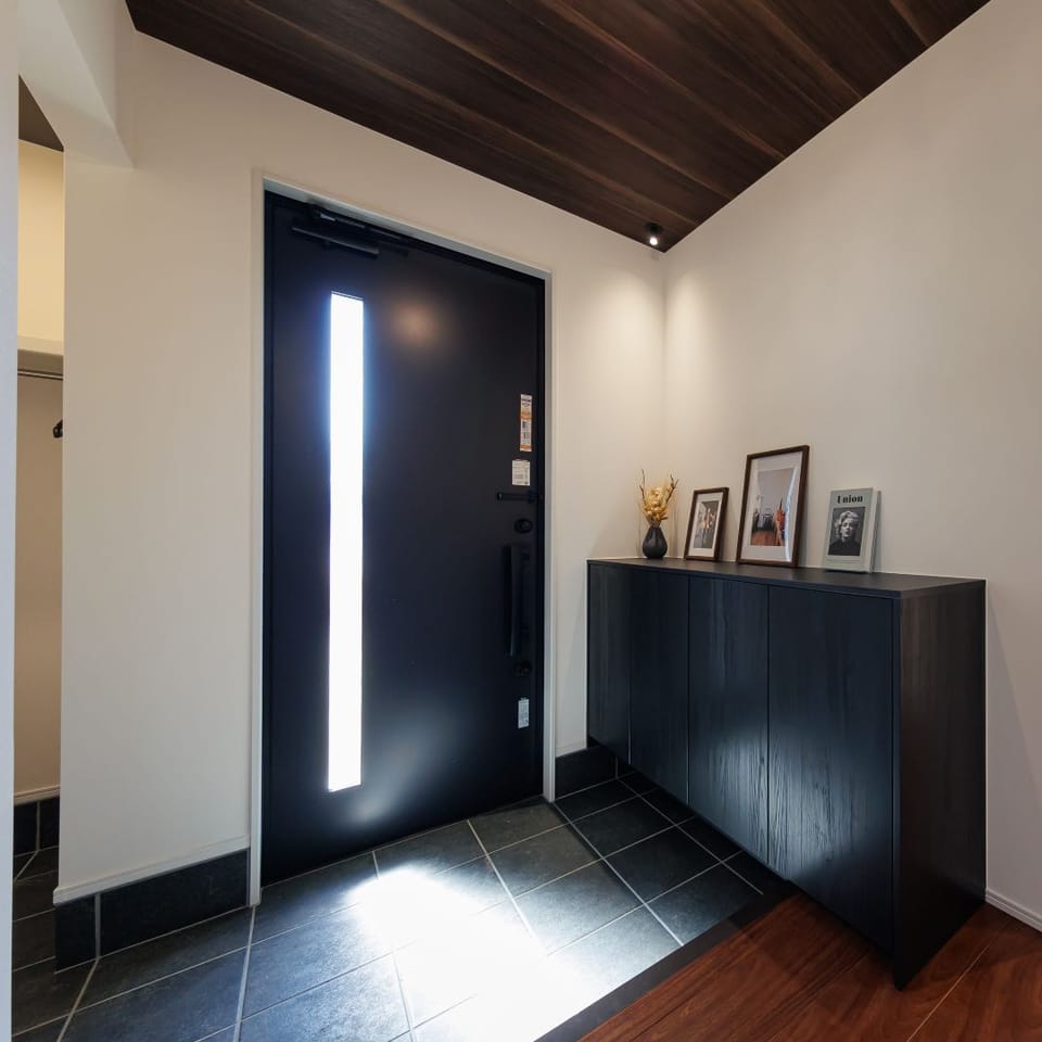 ダークな木目の天井がシックな玄関ホール。黒い木目柄のシューズボックスが上品なワンポイントに。