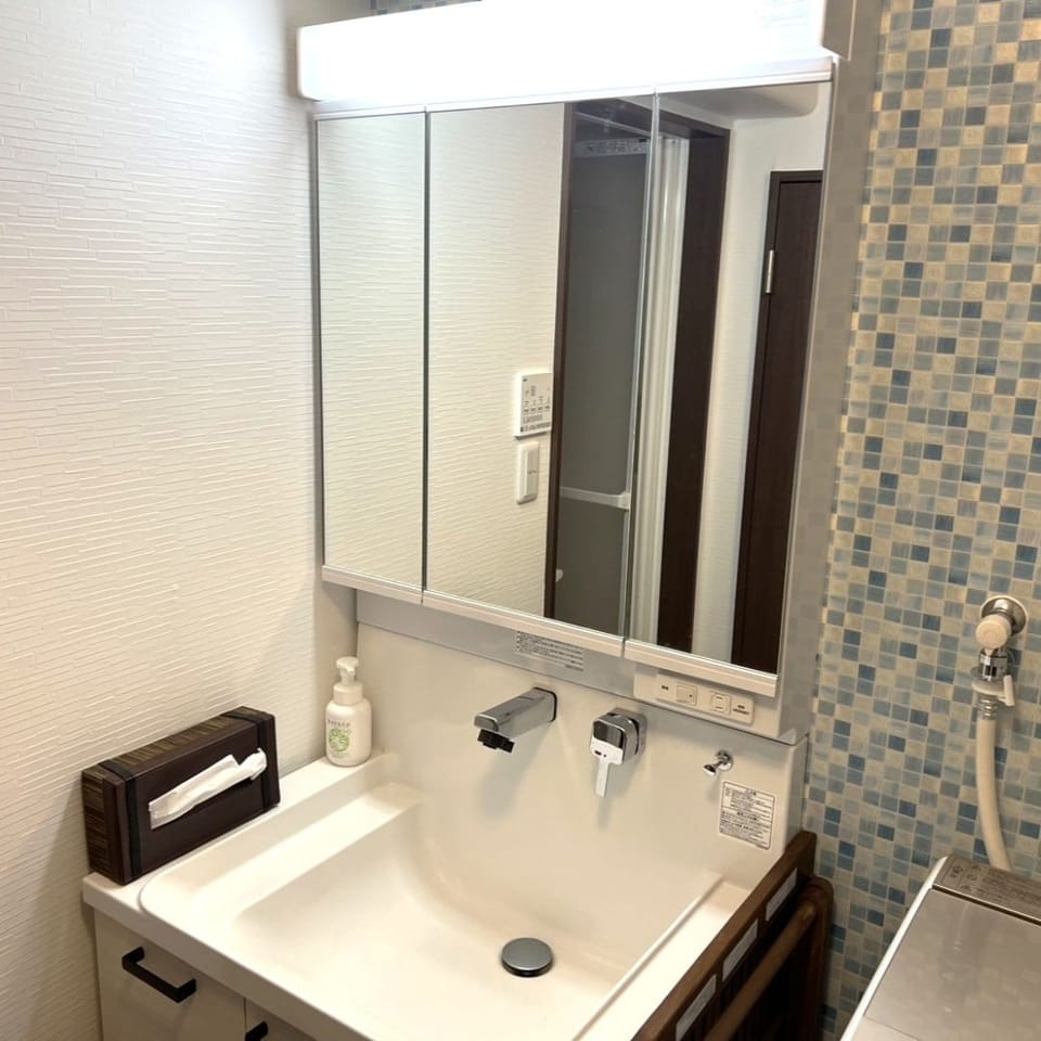 2022年に新品交換済の洗面化粧台。生活感が出にくいお洒落なタイル風クロスがポイント。