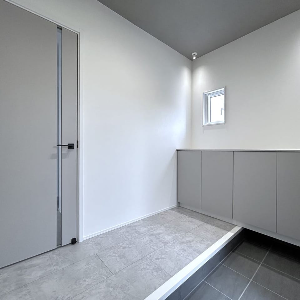 グレーでまとめた柔らかな雰囲気の玄関。エントランスクロークには上着を掛けられるハンガーパイプ付き。