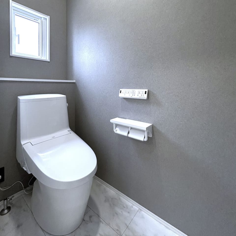 マットなグレーのクロスを採用し、落ち着きのある空間のトイレ。掃除のしやすさに定評のあるLIXIL製。