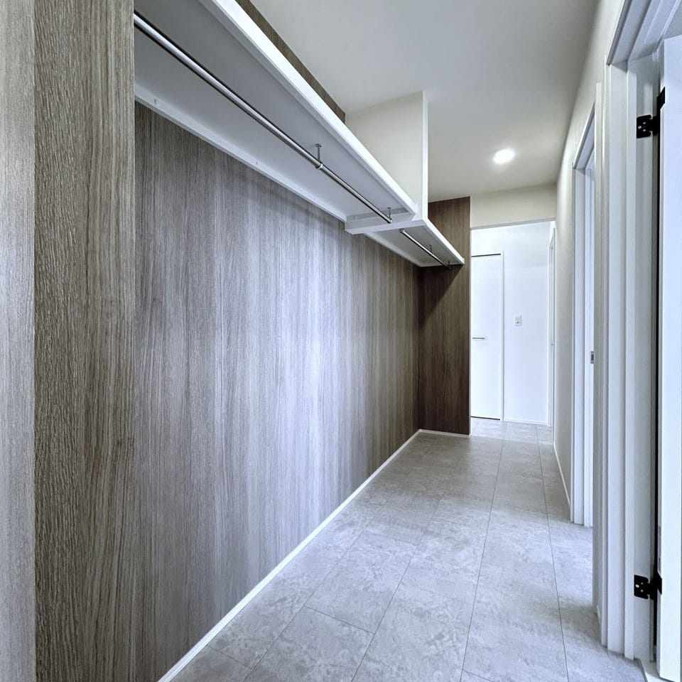 LDK横には通り抜けられるウォークスルークローゼット。家族の衣類をまとめて収納し、生活感をスマートに隠す工夫。