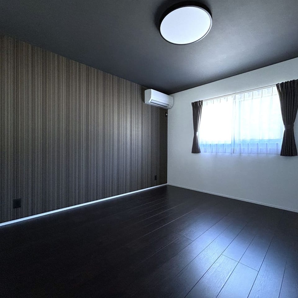 ダークなフローリングとランダムストライプのアクセントクロスで、洗練された大人の空間の寝室に。