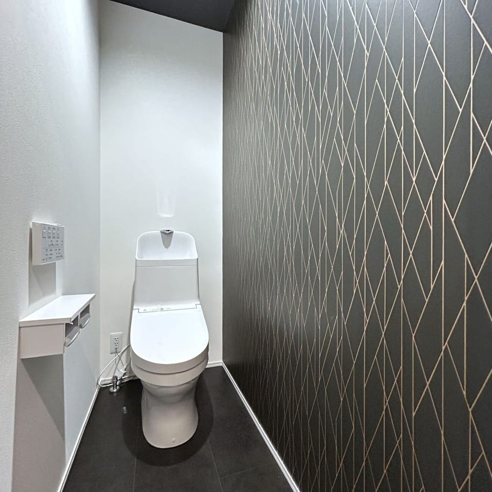 お手入れ簡単なTOTO製トイレを採用。ブラックのアクセントクロスが空間を引き締め、上質で落ち着きのある印象に。