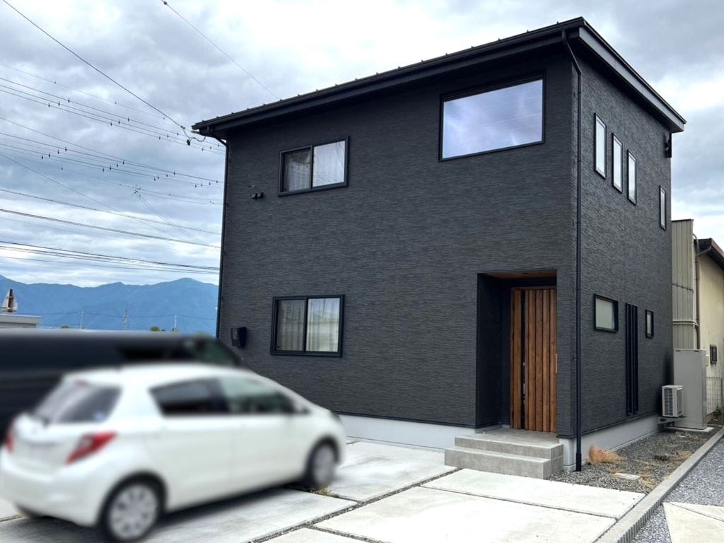 チャコールブラックの外観に、柔らかな木目の玄関ドアがアクセント。外構も綺麗に整備済です。