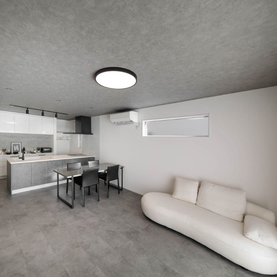 ラフモルタル調のグレーフローリングとコンクリート調の壁紙で統一した、無機質でありながらどこか落ち着くモダンな空間のLDK。