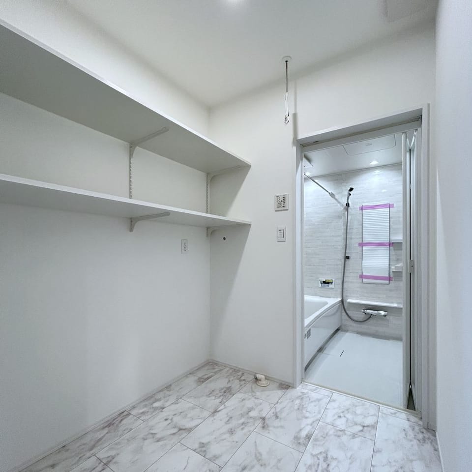 キッチン横に設けた2帖脱衣室は家事ラク動線を意識。グレーで統一し、カルカッタホワイトの床が上品で清潔感のある空間に。