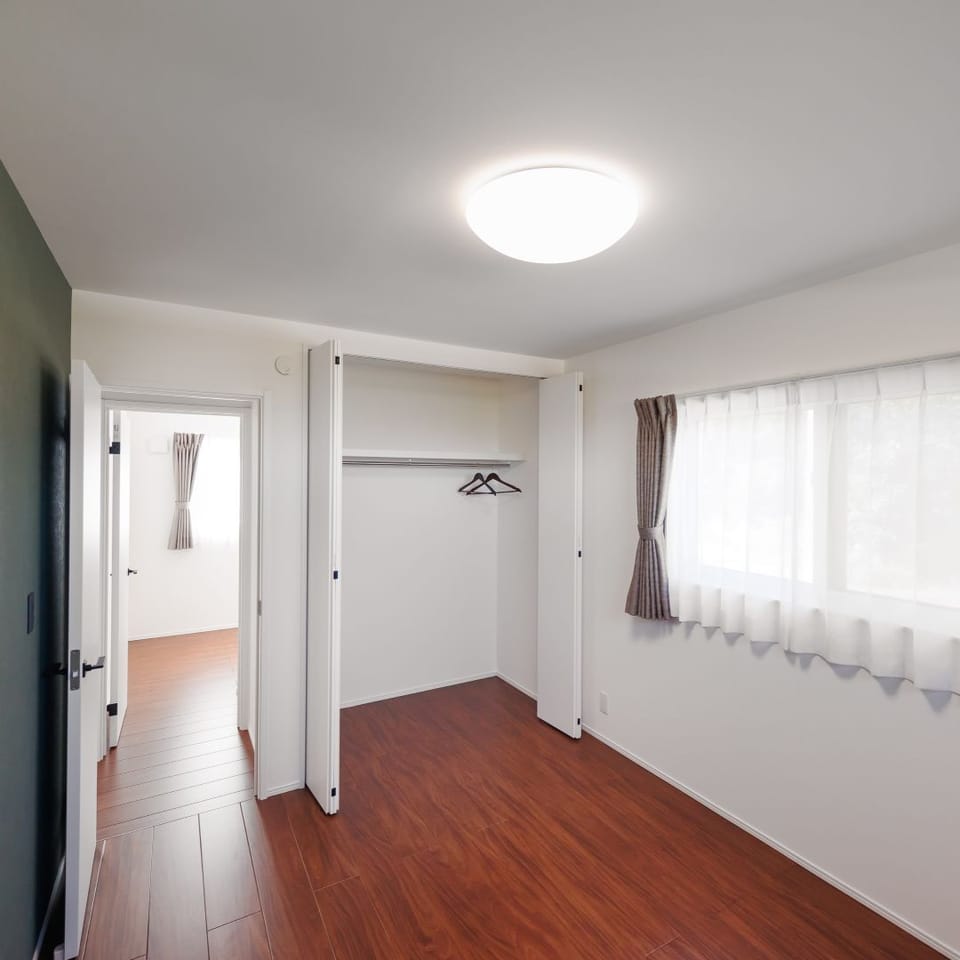 グリーンの石目調アクセントクロスが深みのあるフローリングとマッチする、上品なコーディネートの寝室。