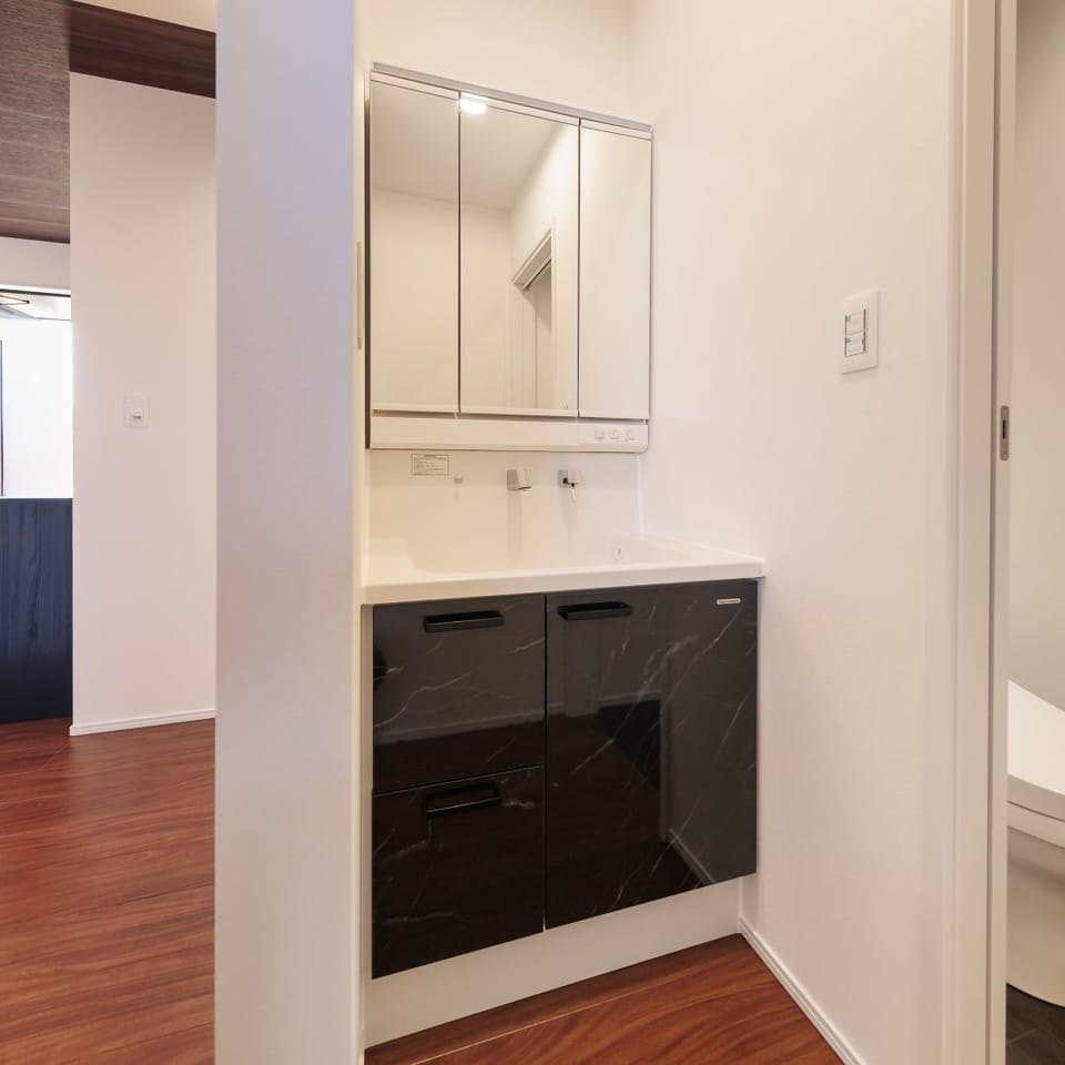 洗面台と脱衣室を分けた使いやすい間取り。家族みんなが快適に使え、ブラックの扉が空間を引き締めます。