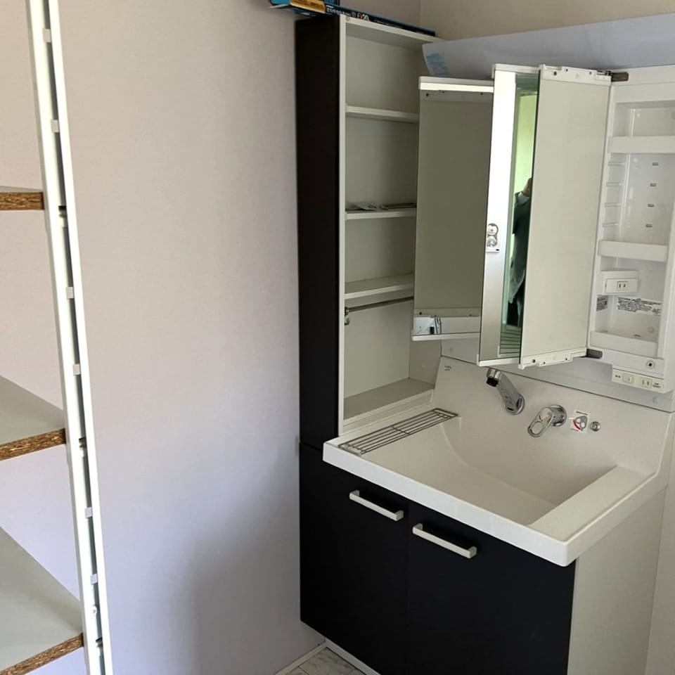 白×ダークブラウンで仕上げ、生活感が出にくい洗面室。リネン類の収納に便利な収納ラック付き。