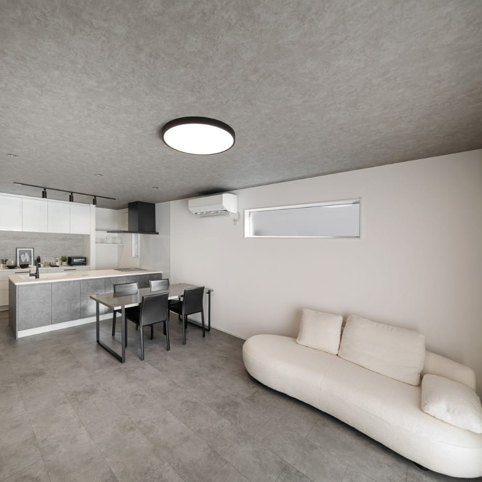 ラフモルタル調のグレーフローリングとコンクリート調の壁紙で統一した、無機質でありながらどこか落ち着くモダンな空間のLDK。