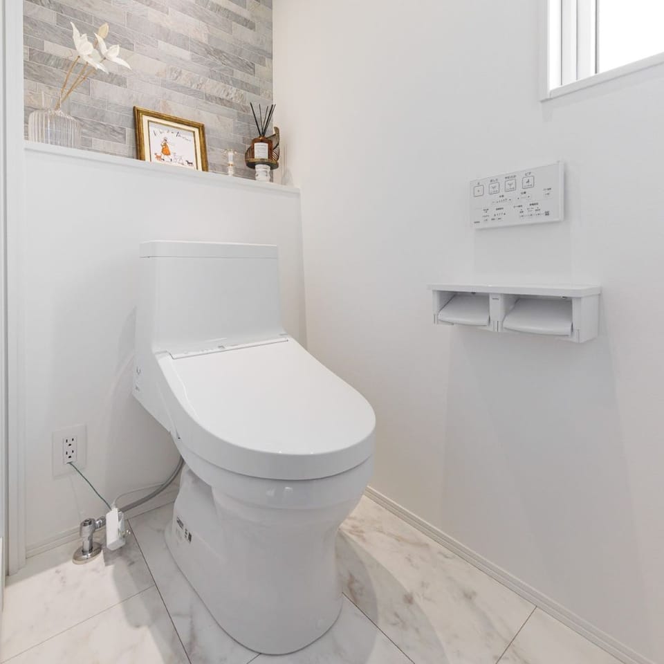 TOTO製トイレを採用した、清潔感のある空間。天然石の風合いを表現したタイル柄アクセントクロスで、落ち着いた印象に。