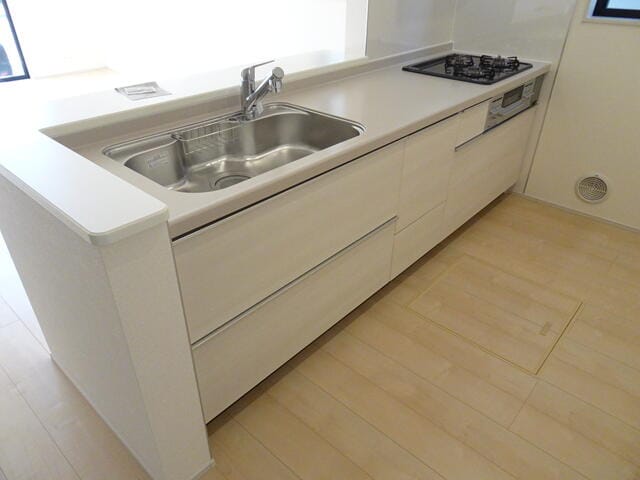 1号棟のキッチン清潔感あるホワイトカラーのキッチン。キッチン